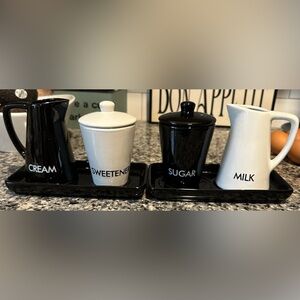 2 OGGI SETS-SUGAR, MILK,SWEETNER & CREAMER SET WITH BASES. Bases have circles.